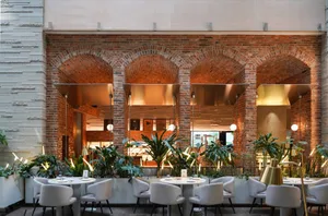 Cozy restaurant interior with brick walls, white tiles, and dim lighting, featuring dining tables and chairs