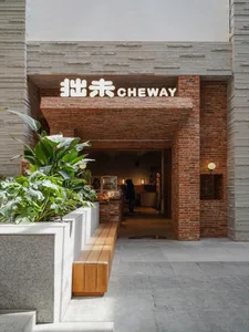 磚牆立面與木質內裝的溫馨亞洲餐廳，盆栽與舒適座位區