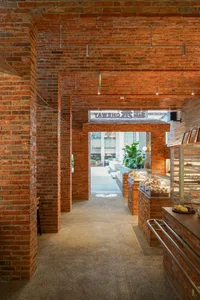 Cozy interior space with red brick walls, potted plants, and multiple dining tables and chairs