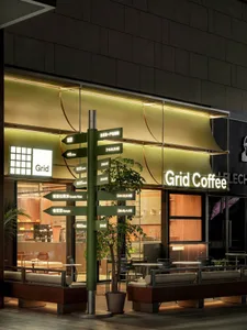 A warm and inviting coffee shop with wood and glass elements, featuring chairs and dining tables for customers to enjoy their beverages