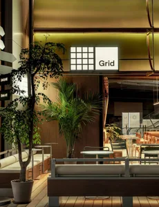 A modern restaurant interior with a large dining area, wooden walls, and potted plants, featuring multiple tables and chairs in a warm and inviting atmosphere