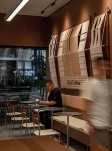 A coffee shop interior with a customer seated at a table, surrounded by chairs and a relaxed atmosphere