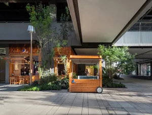 A street food stand with a wooden structure in front of a building, surrounded by people enjoying their meals