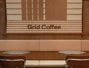 Cozy seating area with two couches and two dining tables in front of a 'Grid Coffee' wall, inviting atmosphere