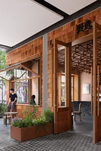 Warm and inviting restaurant interior with wooden walls and floors, featuring a dining table, chairs, and potted plants