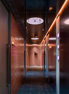 Dimly lit hallway with a brick wall and a pink wall, featuring two doors and a mysterious atmosphere