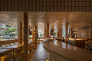 Warm and inviting restaurant interior with wooden tables and chairs, surrounded by comfortable seating and warm lighting