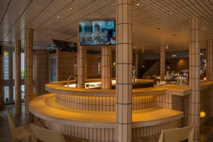 Modern restaurant bar with a TV mounted above it, featuring two chairs and a comfortable atmosphere