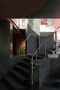 A modern staircase in a residential building with metal stairs and concrete walls, suggesting a functional and stylish design