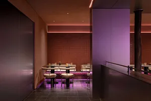 擁有紫色牆面與地板的大型餐廳區域，配有多張桌椅、裝飾花瓶，營造舒適氛圍