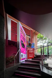 Modern hotel lobby with pink walls, a staircase, and signs including one reading Golden Cat, with a cat present in the scene