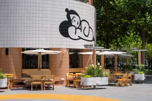 An outdoor dining area with tables, chairs, umbrellas, and potted plants, creating a comfortable atmosphere for meals