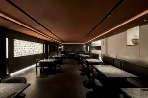 A well-lit restaurant with wooden floors and walls, featuring tables and chairs in a comfortable dining area