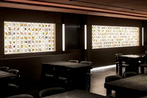A dark and empty restaurant with industrial-style tables and chairs, featuring a moody atmosphere