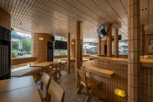A restaurant interior with wooden tables and chairs, TVs on the walls, and a welcoming atmosphere