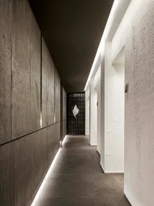 A dimly lit hallway in an old building with white walls and floors, featuring two doors on either side