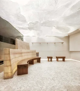 Empty minimalist room with a large window, two benches, and three chairs, featuring a clean and functional atmosphere