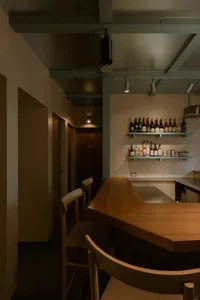 Cozy kitchen with wooden floors and walls, featuring a countertop with bottles and two chairs