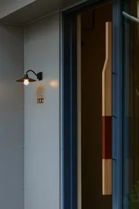 A wooden doorway with a wooden frame, lit by two lights on either side, creating a warm and inviting atmosphere