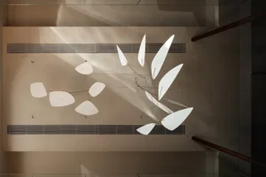 A modern lobby featuring a large white leaf sculpture hanging from the ceiling, surrounded by a clean and minimalist space