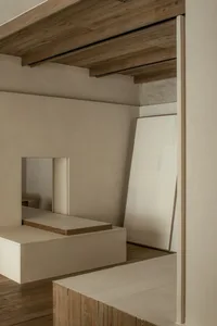 Empty minimalist living space with a white wall, wooden floors, and two mirrors, creating a calm and minimalistic atmosphere