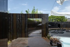 A stone wall and wooden deck create a relaxing outdoor space with comfortable seating and shade from umbrellas