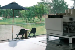 A patio dining area with a table and chairs, shaded by an umbrella, surrounded by a serene forest setting