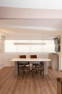 Professional office space with a large white desk surrounded by chairs and a mounted TV in a modern setting