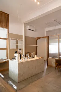 Modern kitchen with a dining area, featuring a countertop with various items, chairs around a dining table, and a functional design