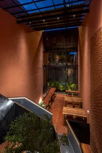 Warm and inviting restaurant interior with wooden tables and chairs, plants on walls and surfaces, and a comfortable atmosphere
