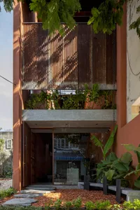 A colorful orange building with large windows and potted plants both inside and outside, creating a lively atmosphere
