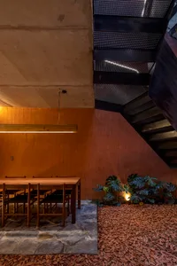 Modern staircase with concrete steps and metal railing, surrounded by a dining table and chairs in a well-lit space