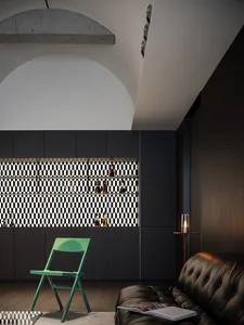 Cozy bar area with a black leather sofa, wooden bar, and green accent chair, surrounded by wine bottles and creating a warm and inviting atmosphere