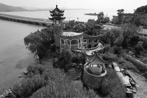 A serene Asian-style building with multiple levels and a distinctive roof structure, situated near water with potted plants and a mix of indoor and outdoor areas