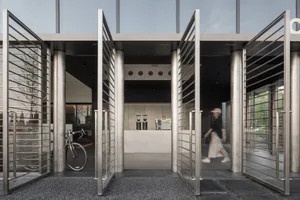 A hotel lobby with a stainless steel door, a dining table, chairs, and a bicycle, surrounded by welcoming and elegant atmosphere