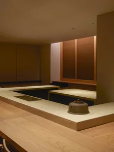 Warm and inviting Asian-style kitchen with wooden walls, stone countertops, and two sinks, set against a neutral background