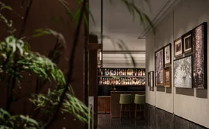 A warm and inviting bar area with a wooden countertop, three chairs, and multiple bottles on display