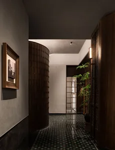A calm and inviting hallway with a tile floor, wooden and glass doors, and two potted plants adding greenery to the space