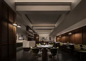 A well-lit dining area with multiple tables and chairs, wine glasses, and a modern interior design
