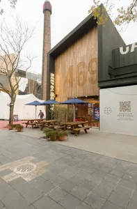 Outdoor dining area with wooden tables, chairs, and umbrellas, creating a welcoming atmosphere for customers