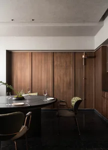 A cozy dining area with a wooden table, chairs, wine glasses, and potted plants, set in a warm and inviting space