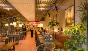 A bustling restaurant dining area with wooden tables, chairs, and people, well-lit for a welcoming atmosphere
