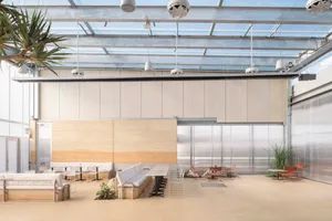 A warm and inviting dining area with a large table surrounded by chairs and potted plants, set within a larger building