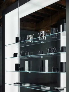 A glass display case in a kitchen area showcases various kitchenware items on multiple shelves, creating a modern and stylish presentation