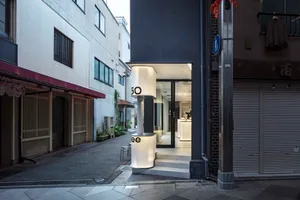 一座黑色建築帶有白色招牌、兩把椅子，以及明亮的日光氛圍