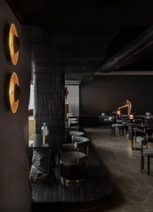 A calm and inviting black and white restaurant with chairs and a woman sitting at a table