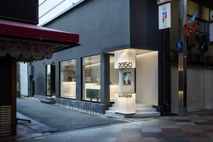 A modern coffee shop with a large sign on the side of the building, featuring a well-lit interior and outdoor seating area