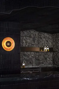 Elegant bar area with a stone wall, two bottles on the countertop, and a sophisticated atmosphere