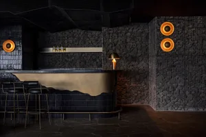 A modern bar area with a gold countertop, black stool, and bottles, creating a sophisticated ambiance