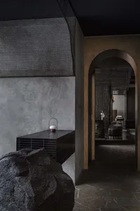 Cozy living area with a stone wall, black countertop, and a large rock in the corner, featuring two chairs and a decorative vase